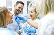 Mutter, Vater und Tochter sind beim Zahnarzt und Tochter untersucht Zähne von ihrer Mutter