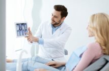 Zahnarzt zeigt Patienten mit einem Tablet Röntgenaufnahmen im Behandlungsraum